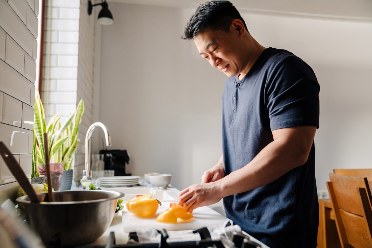 Asian man cutting peppers in the kitchen