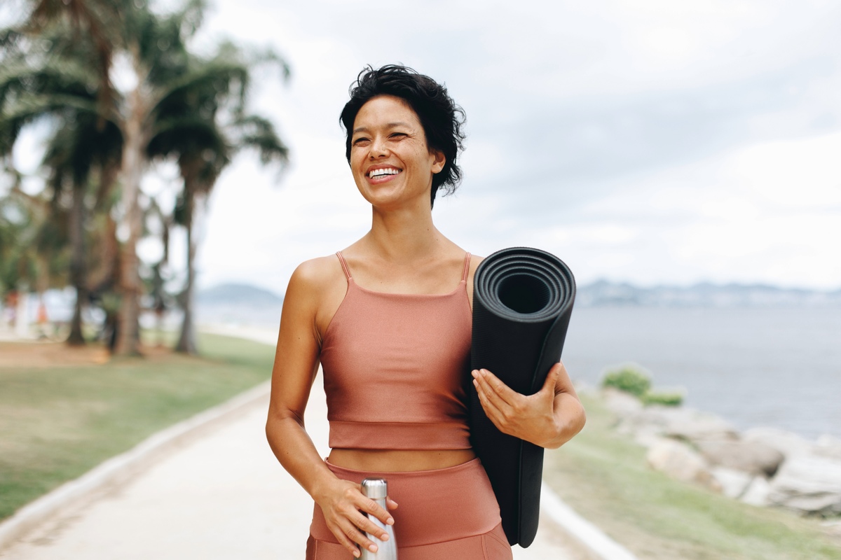 Woman walking with yoga mat outside